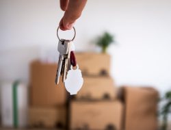 Close-up of the keys of the new empty apartment with moving boxes on the floor